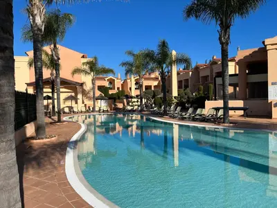 a large swimming pool with palm trees and buildings at Margarida Apartment in Luz