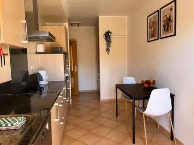 a kitchen with a black table and white chairs at Margarida Apartment in Luz