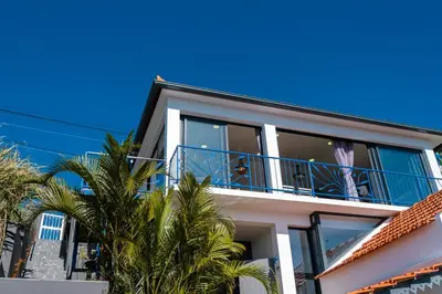 a house with a balcony and palm trees at GuestReady - A marvellous stay in Calheta in Calheta