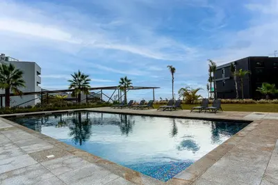 a large swimming pool with chairs and palm trees at Madeira Four Seasons in Funchal
