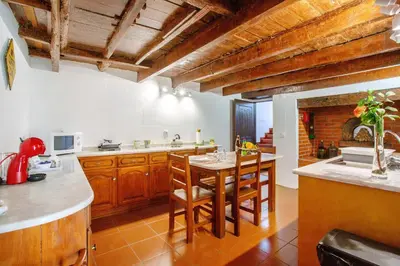 a kitchen with wooden cabinets and a table with chairs at Mother's House in Calheta