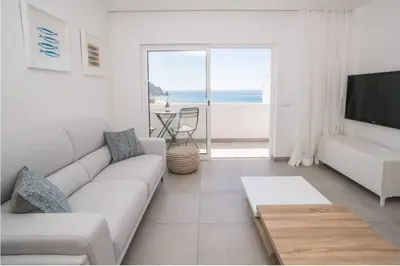 a white living room with a couch and a television at Casa Vista da Praia in Luz
