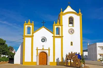 a yellow and white church with a clock tower at Casa Vista da Praia in Luz