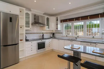 a kitchen with white cabinets and a counter top at Vivenda Kristina in Luz
