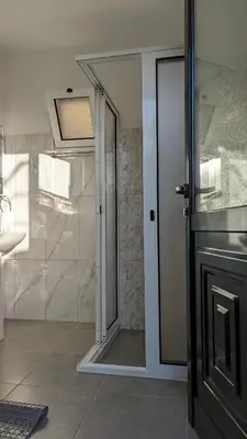a bathroom with a shower and a glass door at Banana Tree House in Ponta do Sol