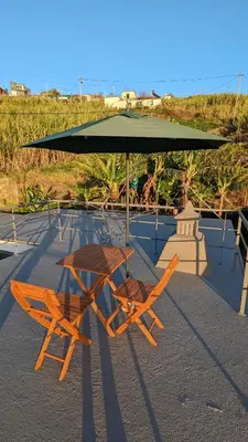 a table and two chairs under an umbrella at Banana Tree House in Ponta do Sol