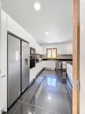 a kitchen with white cabinets and a tile floor at Villa Faísca in São Roque do Faial