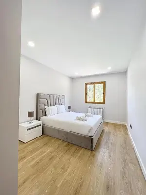 a white bedroom with a bed and a wooden floor at Villa Faísca in São Roque do Faial