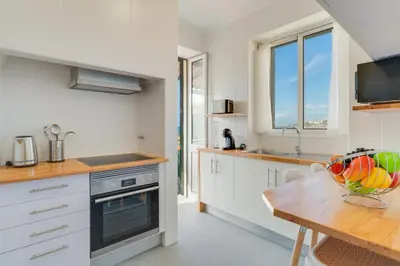 a kitchen with white cabinets and a wooden table at Marias Place by Atlantic Holiday in Funchal
