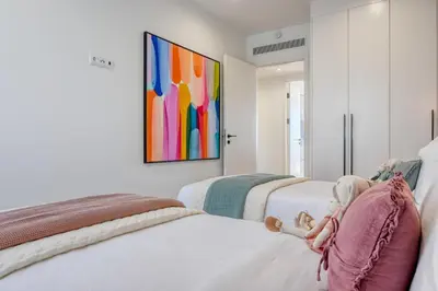 two beds in a room with a painting on the wall at The Place by Nicolene, a Home in Madeira in Funchal