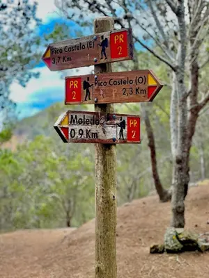 a wooden sign with many signs on a pole at Profetas GuestHouse in Porto Santo