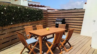 a wooden table and chairs on a wooden deck at Carrapateira Retreat in Carrapateira