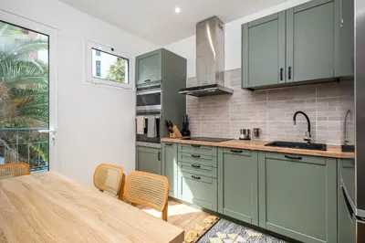 a kitchen with green cabinets and a table with chairs at Cozy Retreat - By WeHost in Funchal