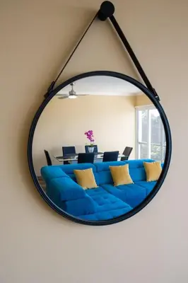 a mirror hanging on a wall with a blue couch at GuestReady - One happy stay in Machico in Santa Cruz
