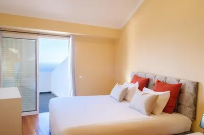a bedroom with a bed with red and white pillows at GuestReady - One happy stay in Machico in Santa Cruz