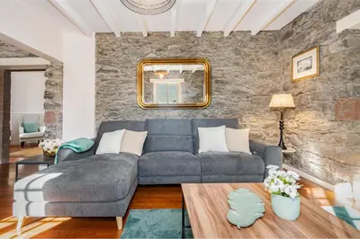 a living room with a gray couch and a stone wall at Du.Val - Madeira Valley Villa in Ribeira Brava