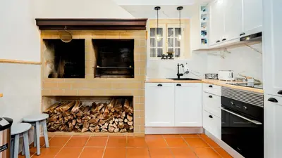 a kitchen with a fireplace with a pile of wood at Du.Val - Madeira Valley Villa in Ribeira Brava