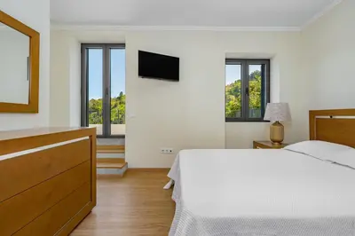 a white bedroom with a bed and a tv at Casa da Quebrada in Santana