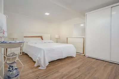 a white bedroom with a bed and a table at Casa da Quebrada in Santana