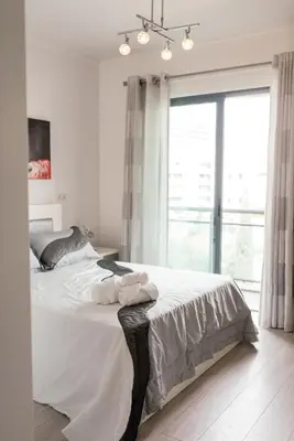 a bedroom with a bed with white sheets and a window at Luxurious Lido-Sun Island X1V Apt.Free parking in Funchal