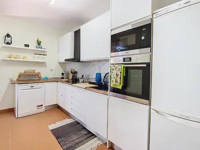 a kitchen with white cabinets and stainless steel appliances at Alojamento Funchal - Silvestre House in Funchal