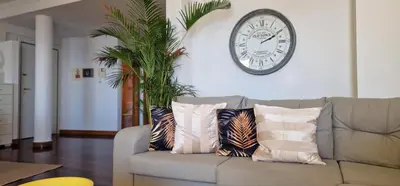 a clock on the wall above a couch with pillows at Glorious Apartment by LovelyStay in Funchal