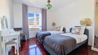 a bedroom with two beds and a desk and a window at Glorious Apartment by LovelyStay in Funchal