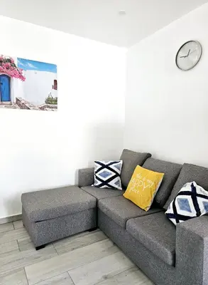 a gray couch in a living room with a clock on the wall at Casa D´Aldeia - Carrapateira in Aljezur