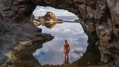 a woman in a bikini standing in a body of water at Sunset house in Paul do Mar