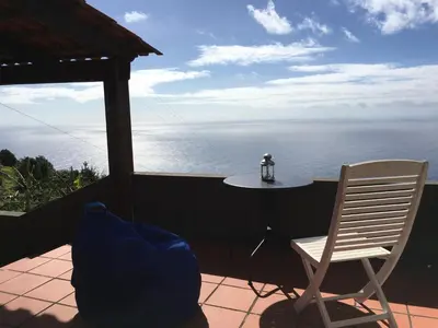 a patio with a table and a chair and the ocean at Casa da Ovelha I Madeira in Fajã da Ovelha