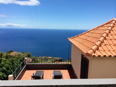 a balcony with chairs and the ocean in the background at Casa da Ovelha I Madeira in Fajã da Ovelha