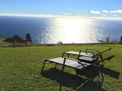 two chairs sitting on the grass near the water at Casa da Ovelha I Madeira in Fajã da Ovelha
