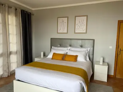 a bedroom with a large white bed with orange pillows at Spring House AL in Arco da Calheta
