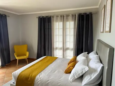 a bedroom with a bed with pillows and a yellow chair at Spring House AL in Arco da Calheta