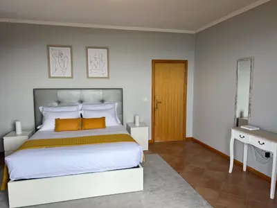 a bedroom with a large white bed with orange pillows at Spring House AL in Arco da Calheta