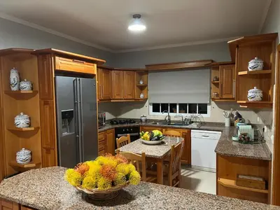 a kitchen with a refrigerator and a table with a bowl of fruit at Spring House AL in Arco da Calheta