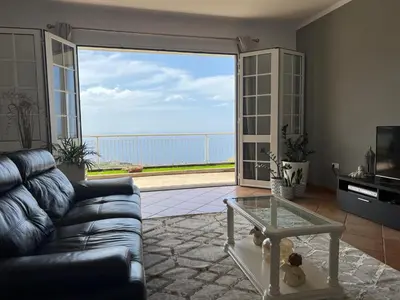 a living room with a couch and a large window at Spring House AL in Arco da Calheta