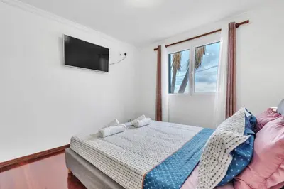 a bedroom with a bed and a tv on a wall at Cozy Seaside Apartment Near Beach and Airport in Caniço