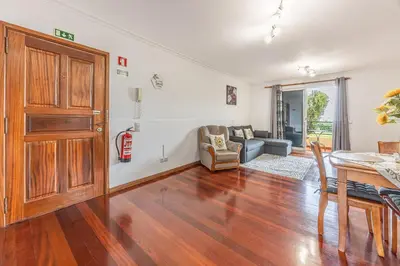 a living room with a wooden door and a table at Cozy Seaside Apartment Near Beach and Airport in Caniço