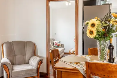 a living room with a table and a chair and a vase of flowers at Cozy Seaside Apartment Near Beach and Airport in Caniço