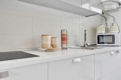 a kitchen counter with three coffee mugs and a microwave at Cozy Seaside Apartment Near Beach and Airport in Caniço