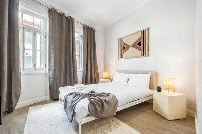 a white bedroom with a bed and two windows at Ponte Nova Studios in Funchal