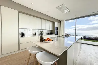 a kitchen with white cabinets and a large window at Villa OceanAIR by LovelyStay in Prazeres
