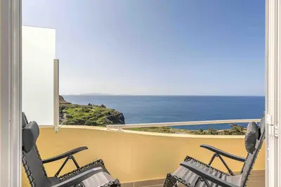 two chairs on a balcony looking out at the ocean at Portinho Mar Apartment in Caniço