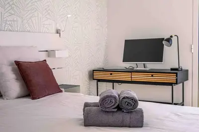 a bedroom with a bed with a desk and a tv at Portinho Mar Apartment in Caniço