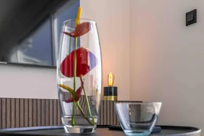 a vase with a flower in it on a table at Portinho Mar Apartment in Caniço
