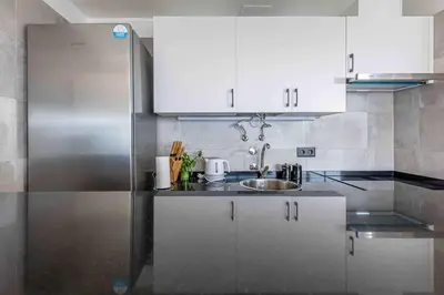 a kitchen with a sink and a stainless steel refrigerator at Portinho Mar Apartment in Caniço
