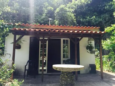 a pergola and a table in front of a house at Moinho do Comandante in Faial