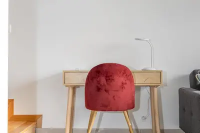 a desk with a red chair next to a couch at Costa Apartment II - Linda Vista in Caniço