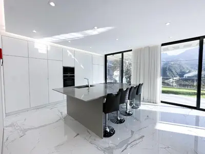a white kitchen with a long table and black chairs at Villa Montana in São Vicente